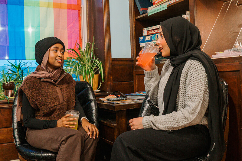 Two women sit talking in the corner of a local coffee shop enjoying their drinks.