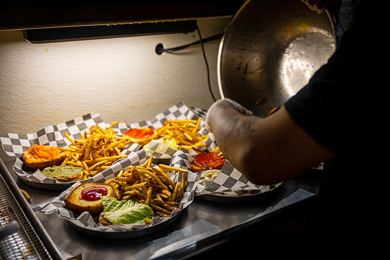 Plates of burgers get french fries dumped onto them at Honest Abe's.