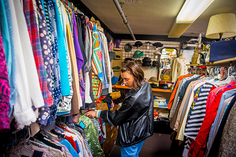 A woman looks through racks of clothing.