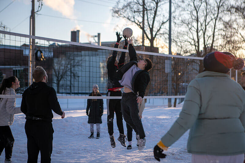 A man jumps at the net while playing volleyball during an outside winter game!